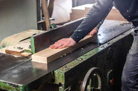 Carpenter working on woodworking saw machines in carpentry shop, industrial concept