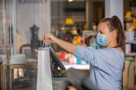 Saleswoman or shopgirl hands over the recepit or invoice by the shopping in the shop center, cloth sale conceptの写真素材