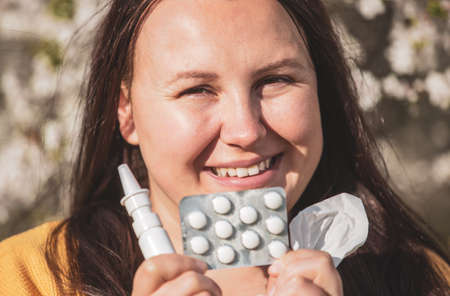 Allergy concept, young woman with pills or drugs and nose or nasal spray against the strong allergy...