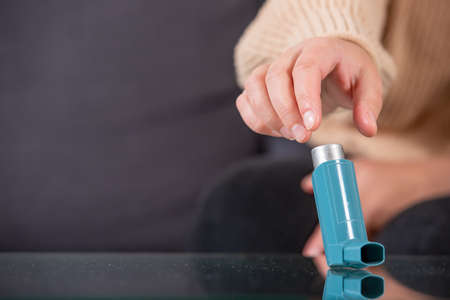 Young woman looking for an asthma inhaler during strong asthma attack, cannot breathing, healthcare conceptの写真素材