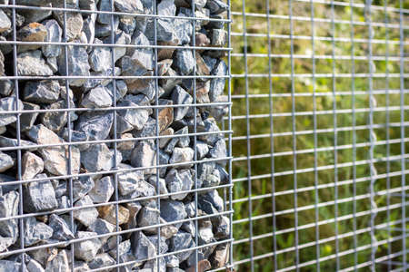 Small granite stones behind a metal mesh, design fence, garden conceptの写真素材