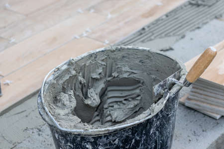 The hands of the tiler lying or installing modern, ceramic tile above cement on the garden terrace , tiling floor, building conceptの写真素材
