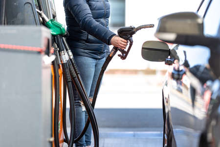 High prices of petrol and diesel fuel ath the petrol station, young woman refueling the car, economic crisis conceptの写真素材