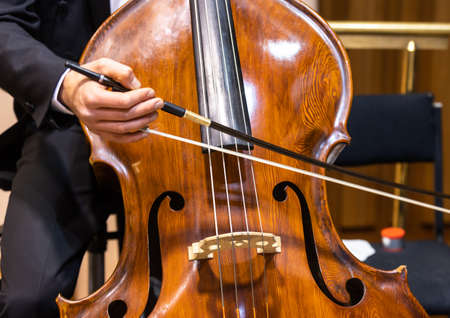 Hands of a musician with a bow playing the double bass in philharmonic orchestraの写真素材