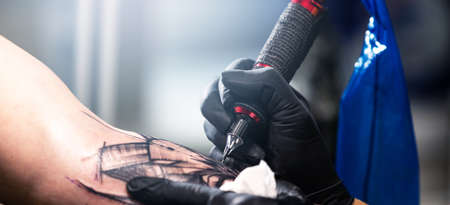 Close up of a tattoo artist tattoos a black tattoo with paint, tattoo fill out a tattoo circuit, tattoo processの写真素材