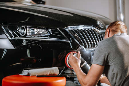 Car details concept - hands with orbital polisher in a car studio, detailingの写真素材