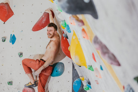 Young climber climbing on the boulder wall indoor, rear view, concept of extreme sports and...