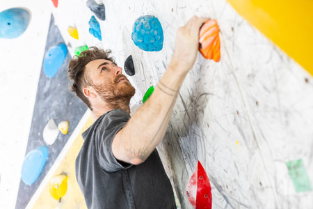 Young climber climbing on the boulder wall indoor, rear view, concept of extreme sports and boulderingの写真素材