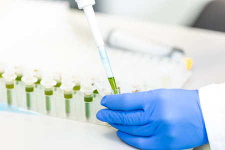 Scientist with dropper dripping liquid into a test tube in scientific laboratory, concept of pharmaceutical environmentの写真素材