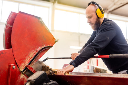 Professional carpenter cutting raw wood to firewood pieces, manufacturing wood concept