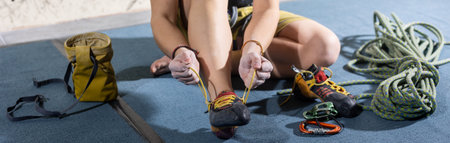 Young female climber tying laces on climbing shoes, preparing for the climbing the wall in the climb centerの写真素材