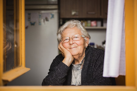 Lovely portrait of smilling grandmother by the window at a house