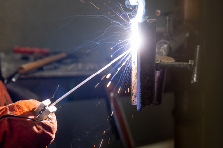 Detail to welding process of metal parts, using a welding machine, bright sparks and flashes,...