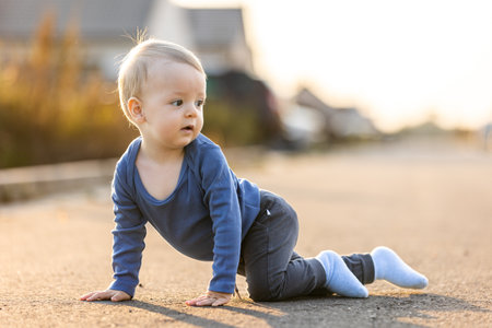 Adorable baby boy crawling on the road at sunset
