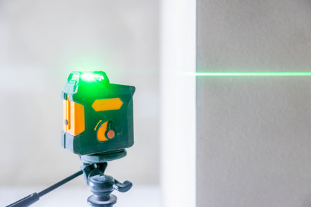 Cross line laser level tool projecting green beam on wallの写真素材