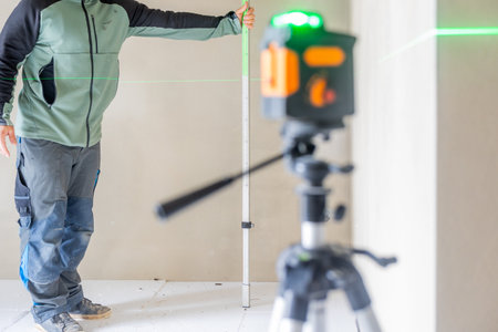 Construction worker using laser level and measuring rod on siteの写真素材