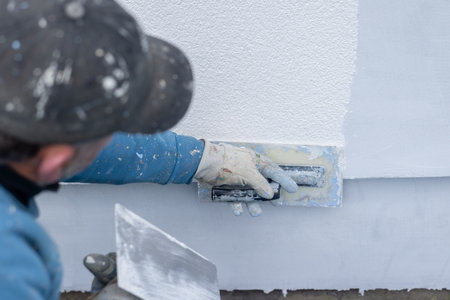 Construction worker applying plaster stucco to a wall for renovation and finishingの写真素材