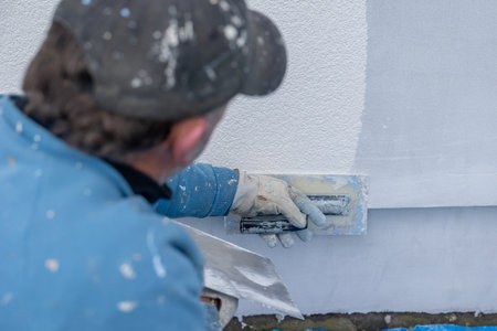 Construction worker applying fresh stucco plaster to an exterior building wallの写真素材