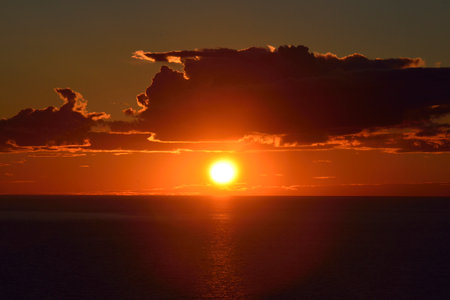 Orange Sun Sets Over Calm Waters at Sunsetの写真素材