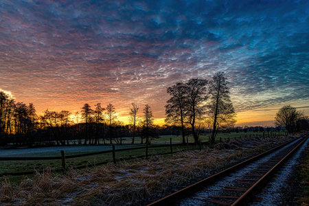 Spectacular Sunset Over Railway, Field, Grass, Trees, and Cloudsの写真素材