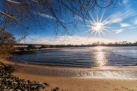 Tranquil Riverside Scene with Sunlight and Blue Skyの写真素材