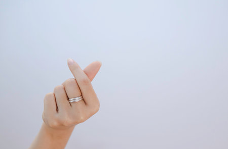 female hand showing small heart on a white isolated background, closeup mini heart sign by women handの写真素材