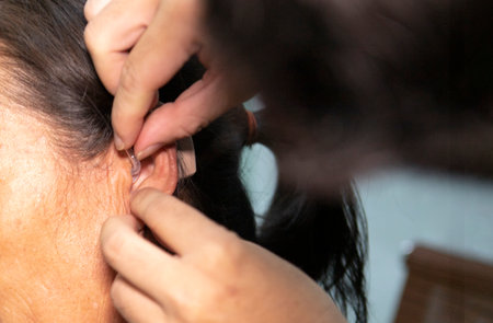 An old man wears a hearing aid, closeupの写真素材