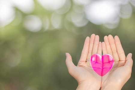 two empty female beautiful hands open with palms up closeup of top view 3d red heart blur backgroundの写真素材
