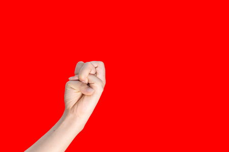 Female hand with clenched fist isolated on red background with copy space.の写真素材