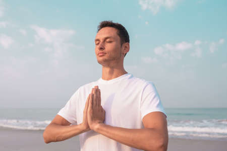 happy guy sits on the seashore and meditates.の写真素材