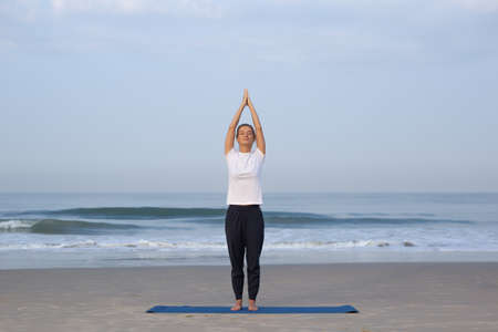 young girl on the beach doing yogaの写真素材