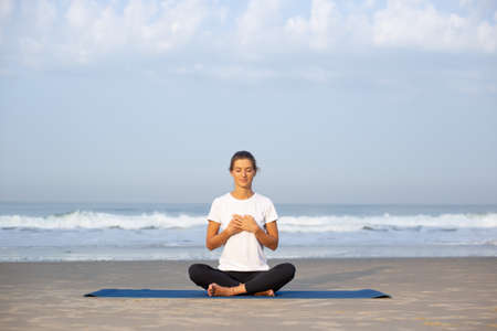 young girl on the beach doing yogaの写真素材