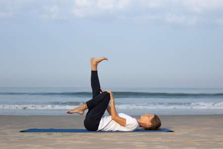 young girl on the beach doing yogaの写真素材
