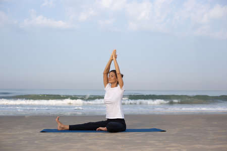 young girl on the beach doing yogaの写真素材