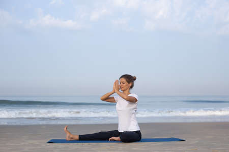 young girl on the beach doing yogaの写真素材