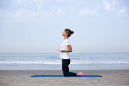 young girl on the beach doing yogaの写真素材