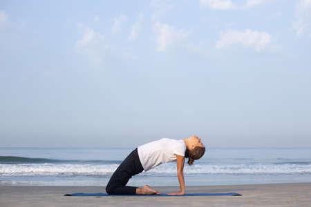 young girl on the beach doing yogaの写真素材