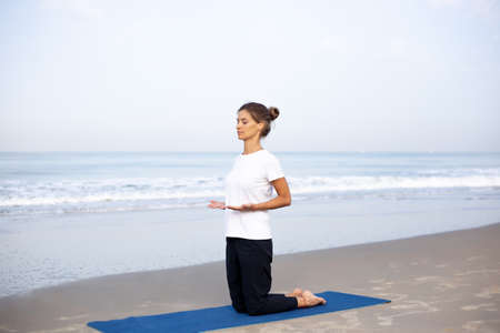 young girl on the beach doing yogaの写真素材