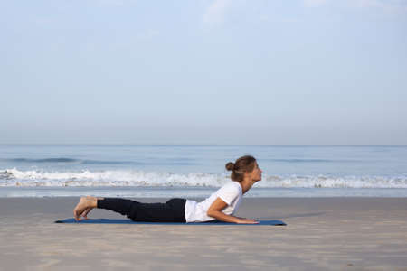 young girl on the beach doing yoga. in white clothesの写真素材