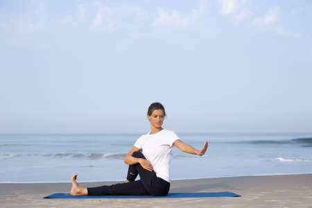 young girl on the beach doing yoga. in white clothesの写真素材