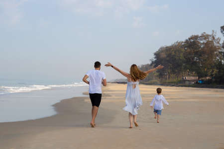 family mom dad child walking along the seashoreの写真素材