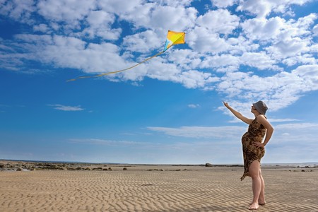 A pregnant woman runs into the sky kiteの写真素材