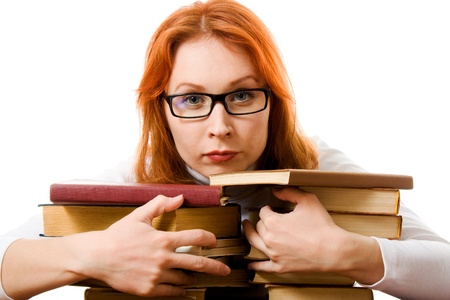 Beautiful red-haired girl in glasses reads book on a white background.の写真素材