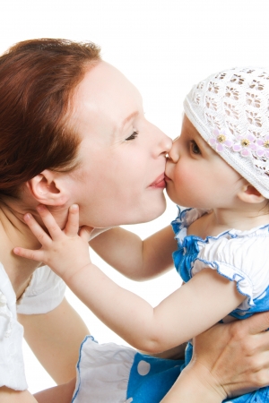 Mother kissing her daughter on a white backgroundの写真素材