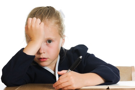 Schoolgirl writes at a table on a white background.の写真素材