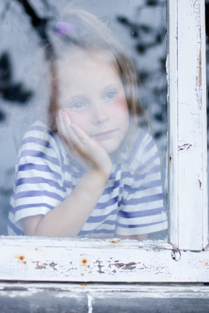 young girl looking from window on the other sideの写真素材