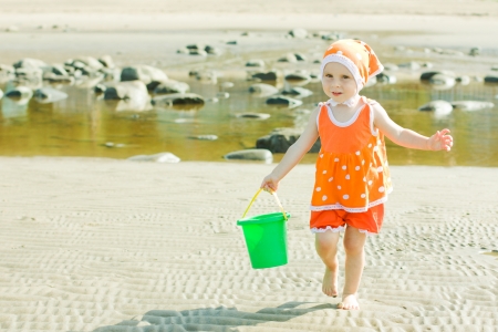The little girl on the beach is water in the bucket.の写真素材