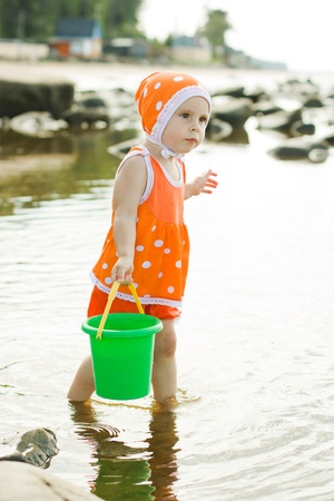 The little girl on the beach is water in the bucket.の写真素材