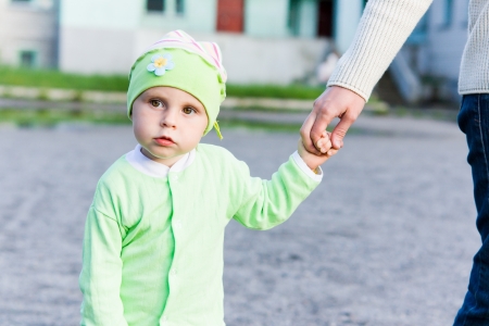 Little kid walking down the street and holds mom's hand.の写真素材