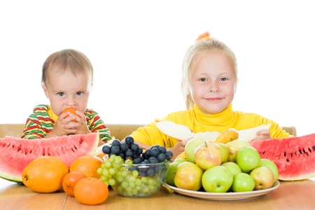 Two children eat fruit at a table on a white background,  concept of health care and healthy child nutritionの写真素材
